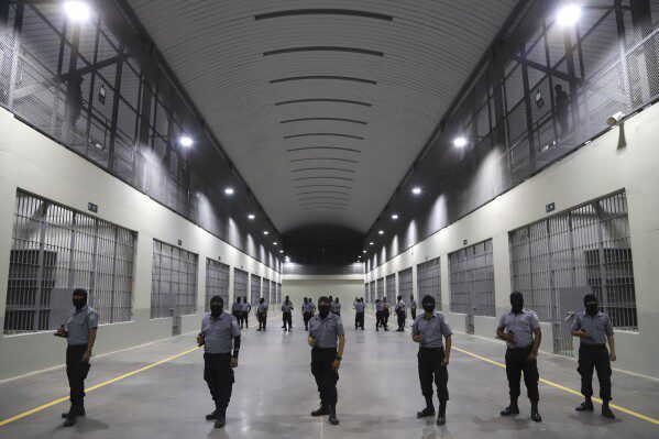 Le guardie carcerarie si trovano fuori dalle celle detenute durante un tour mediatico presso il Centro di gabinetto del terrorismo, o Cecot, a Ticoloca, El Salvador, 2 febbraio 2023 (foto AP/Salvador Meendez, file)